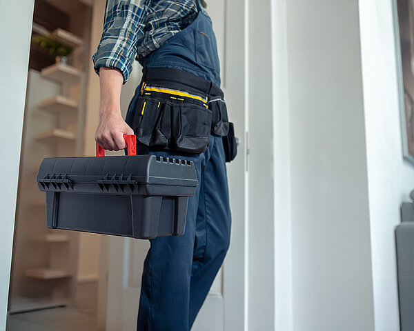 Techniker mit Werkzeugkoffer betritt ein Haus zur Installation.