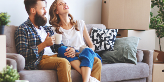 Frau und Mann sitzen auf dem Sofa, rundherum stehen Umzugskartons