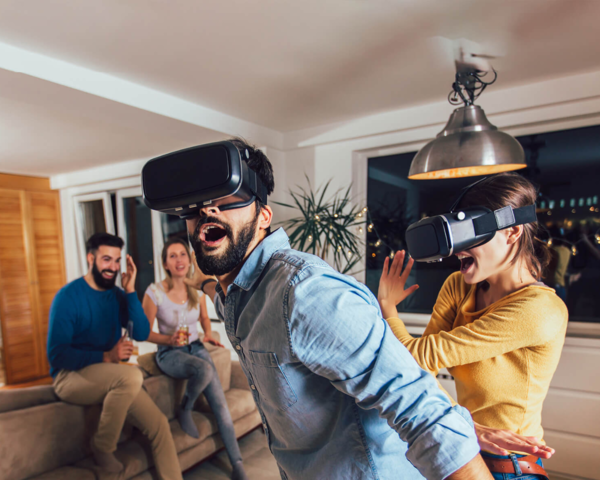 Menschen erleben gemeinsam Virtual-Reality mit VR-Brillen im Wohnzimmer.