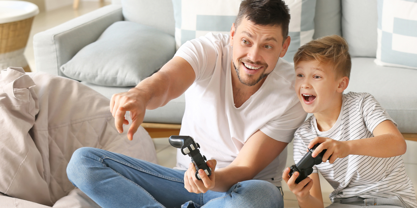 Ein Vater und sein Sohn erleben gemeinsam einen spannenden Gaming-Moment – ein Symbol für schnelle Reaktionszeiten, stabile Verbindungen und die Vorteile einer leistungsstarken Glasfaser-Internetverbindung im Alltag.