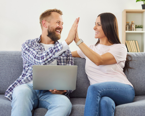 Paar freut sich über schnelles Internet mit Laptop auf dem Sofa