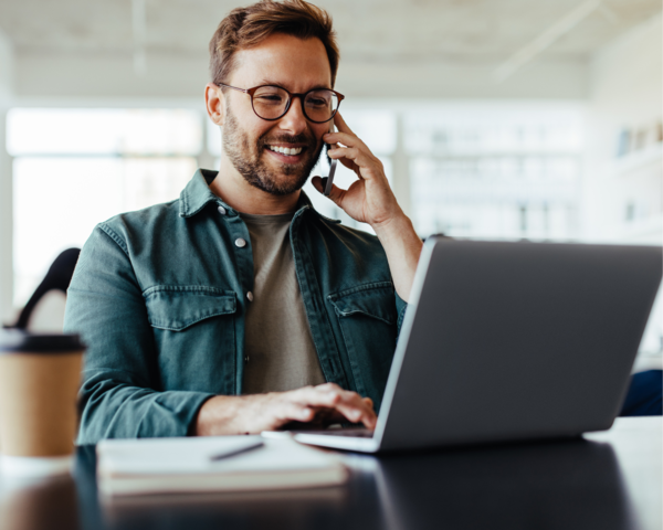 Person arbeitet am Laptop und telefoniert im Büro