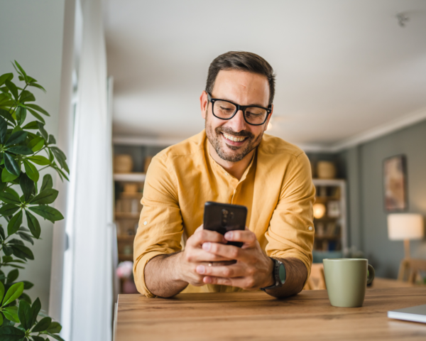 Mann lehnt sich auf den Tisch und bedient ein Telefon