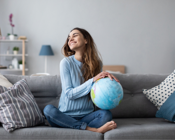 Frau sitzt auf dem Sofa mit einem Globus in den Händen