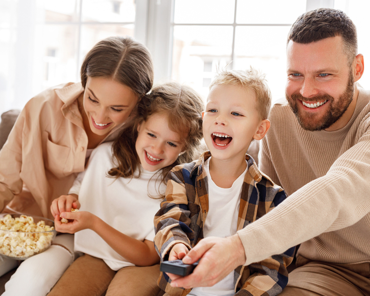 Lachende Familie beim Fernsehen auf dem Sofa